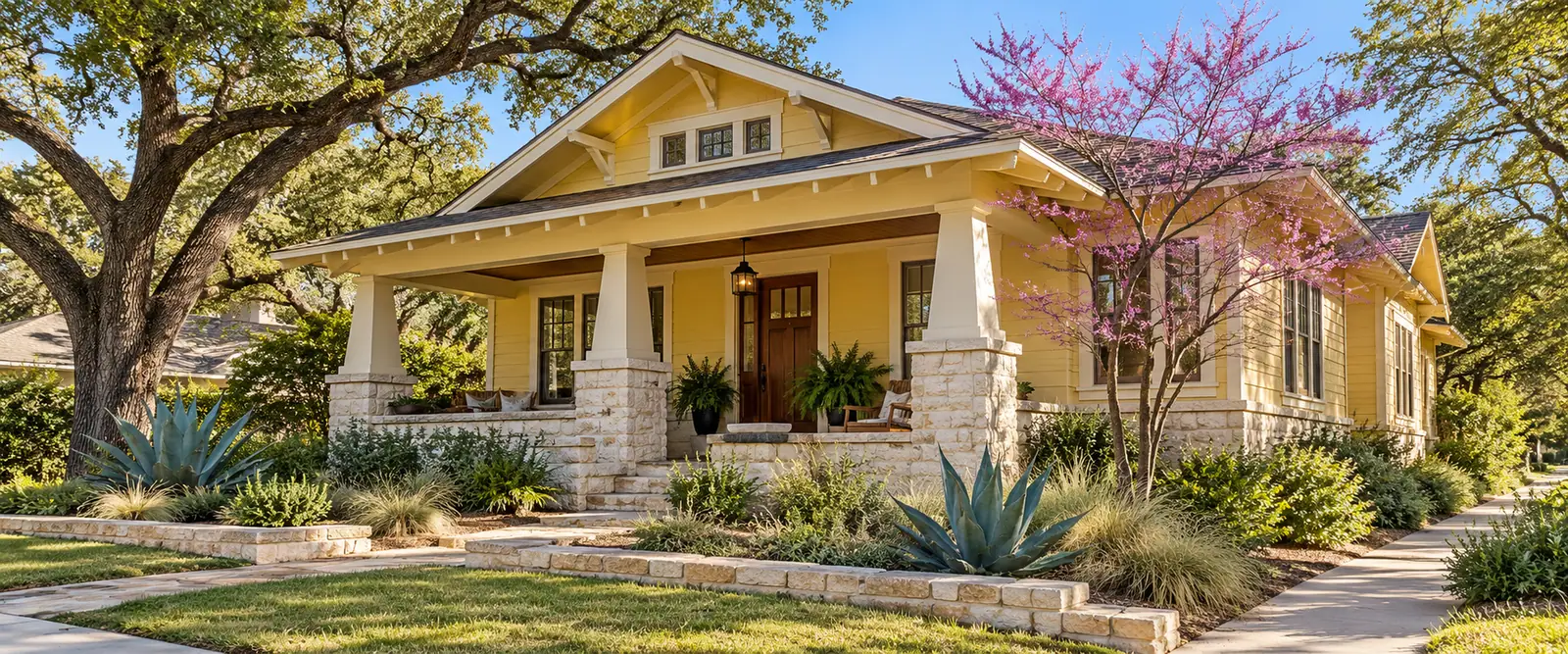 AI-generated yellow Craftsman bungalow with limestone porch piers, a flowering redbud, live oak and agave.